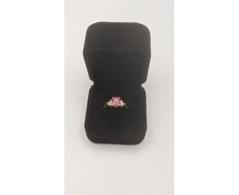 A ruby and diamond 18ct yellow gold ring with an oval cut ruby in a four claw setting flanked by two brilliant cut diamonds, 