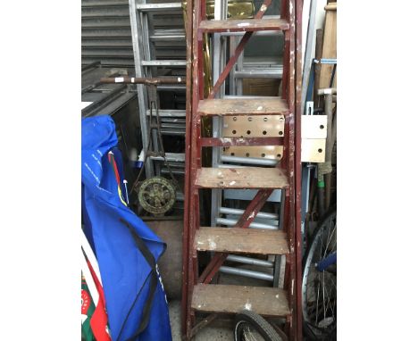 An old metal grass roller, a set of aluminium extending ladders, a workbench and a set of wooden stepladders. 