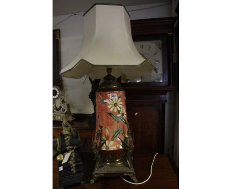 A ceramic and gilt metal oil lamp (converted for electric) the ceramic reservoir painted with flowers and foliage 