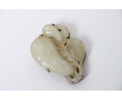 A carved jade brooch with silver mount
