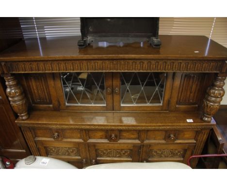 A large oak court cupboard with lead light glazed doors and oak supports 