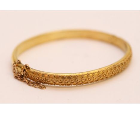 A 15ct yellow gold bangle with raised decoration