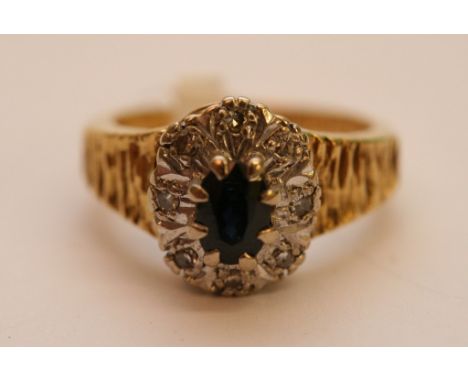 A ladies 18ct yellow gold ring set with a central sapphire with diamond set surround