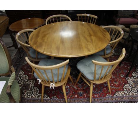 An Ercol light wood dining room suite comprising a dining table with six chairs and a sideboard 