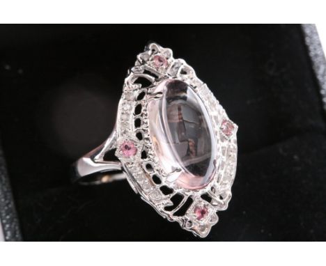 A ladies 14ct white gold ring set with a pink quartz cabochon with ornate surround set with diamonds and topaz