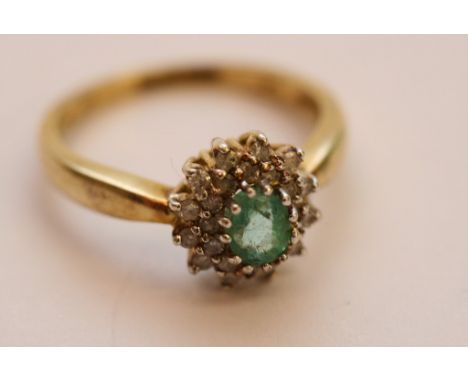 A ladies 9ct yellow gold ring set with a central oval cut emerald with diamond surround