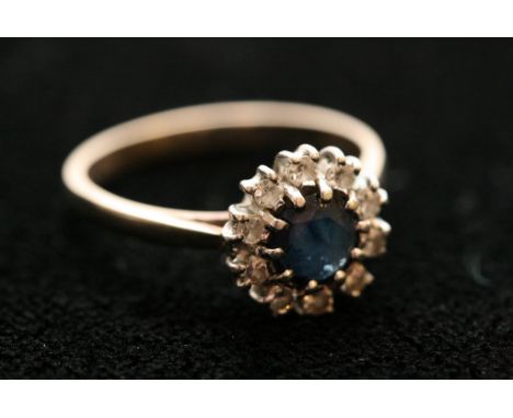 A 9ct gold ring set with sapphire and diamond surround