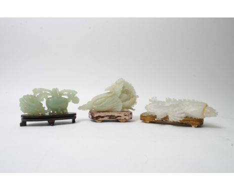 A collection of three white to green Chinese hardstone carvings of foliate form on wooden stands, possibly Jade