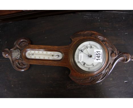 A small carved oak wall barometer with an enamel dial 