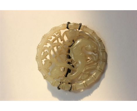 A circular Chinese jade brooch pierced with fish within a bamboo border