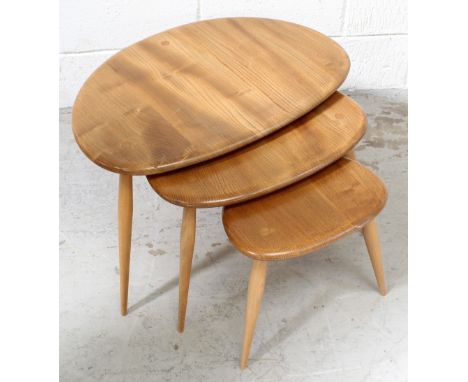 An Ercol pebble-shaped light wood nest of three coffee tables.