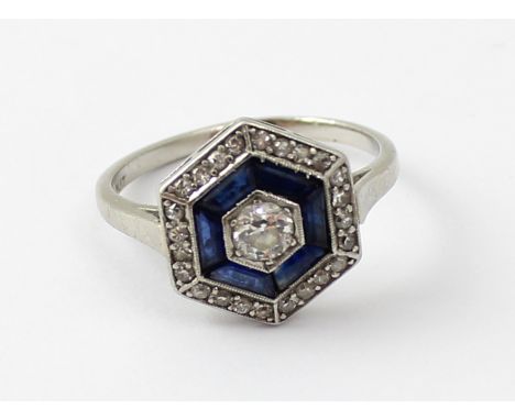 An Art Deco platinum diamond and sapphire hexagonal cluster ring with approx 0.2ct central stone, set within six baguette-cut