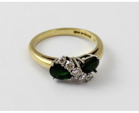 An 18ct chip diamond and emerald crossover ring set with two teardrop shaped emeralds, and with five graduated diamonds separ