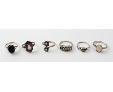 A set of six silver dress rings including a black onyx example, a hematite solitaire, a white opal solitaire, an amethyst-col