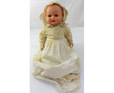 A vintage Henrick Handwerk composite doll with mechanical opening eyes, dressed in a cotton christening gown.