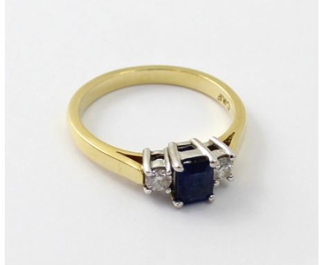 An 18ct gold ladies' ring, central emerald cut blue sapphire and diamond to either side, size M, approx 3.5g.