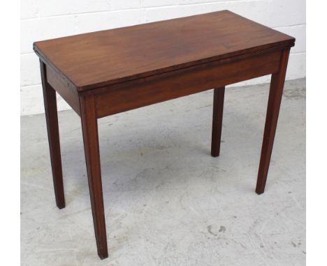 A late 19th/early 20th century mahogany fold-over card table on tapering supports, length approx 92cm.