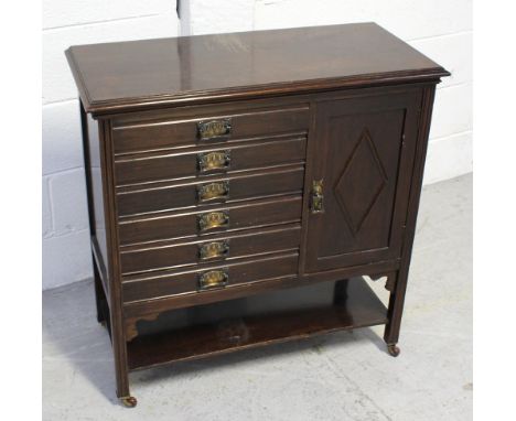 A mahogany music cabinet, six sheet music drawers to one side and a small cupboard door with lower shelf, on reeded supports 