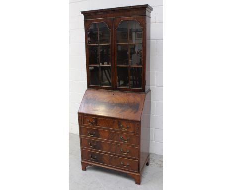 An Edwardian mahogany bureau bookcase, twin glazed doors, interior shelf, over a drop-down desktop over four drawers to shape