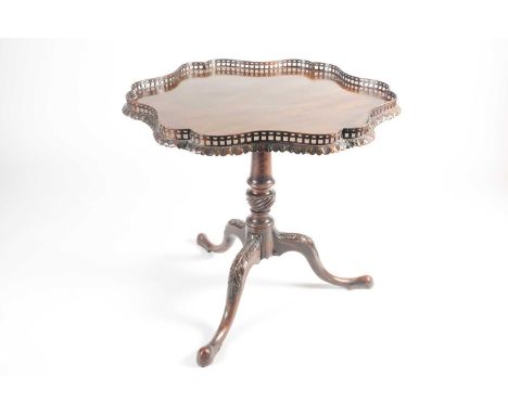 A late George III, mahogany flip-top tripod silver table with a shaped outline and a pierced gallery. With gadrooned urn colu