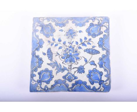 A Persian pottery blue and white tile, 18th/19th century, decorated with a central floral spray framed by stylised flower hea