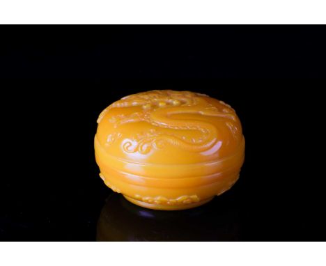 A Chinese, Peking yellow glass, circular incense box. Carved with a five claw dragon and pearl amidst stylized clouds. Bearin