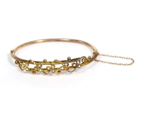 A seed pearl bangle, the crossover front with a motif of seed pearl set trailing vines, to a plain hinged back, measures 6cm 