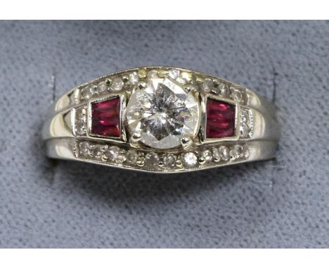 An Art Deco style ruby and diamond ring, a round brilliant cut diamond in a claw setting, spaced by pairs of calibré cut rubi