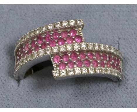 An 18 carat white gold ruby and diamond crossover ring, two rows of round cut rubies between rows of round brilliant cut diam