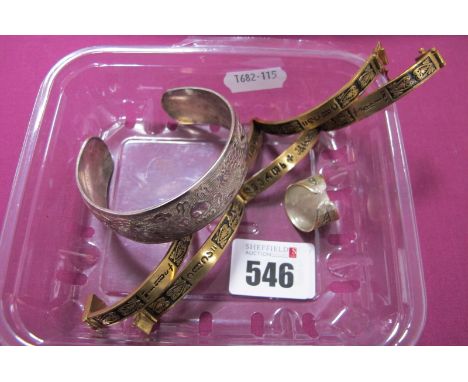 A Wide Oriental Style Bangle, depicting a dragon and bird design; together with two Middle Eastern style panel bracelets and 