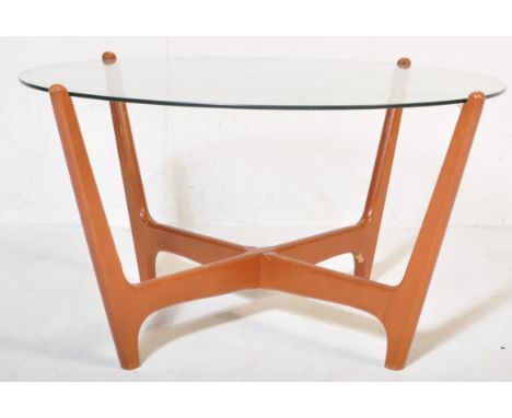 A mid 20th Century retro vintage atomic teak and glass coffee table. Having a circular glass panel resting on two teak wood s