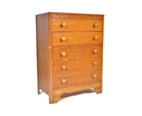A vintage 20th century circa 1940s light oak chest of drawers having a carved floral frieze over a bank of five drawers with 