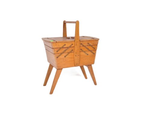A vintage retro mid 20th century circa. 1960s teak wood metamorphic sewing box having bar handle with hinged extending compar