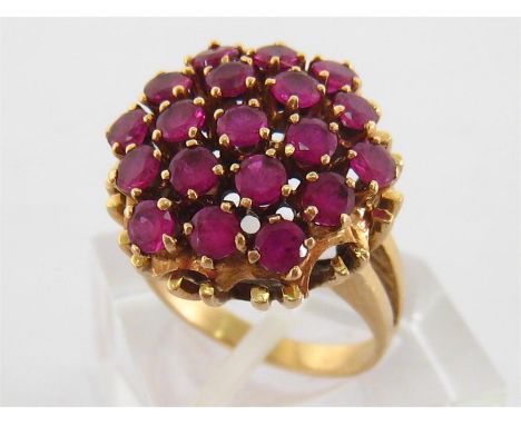 A 14 carat gold and ruby cluster ring, the cluster composed of 19 uniform round cuts each 3mm diameter, to bifurcated shoulde