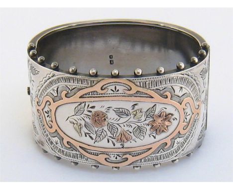 A Victorian silver and rose gold cuff bangle, Birmingham 1886, the front engraved with flowers within a scrolling border, acc