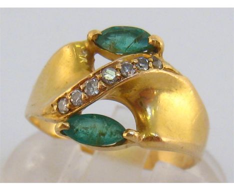 An 18 carat gold, emerald and diamond ring, the two navette cut stones 5.8mm long, the shank stamped ‘750’, finger size J/K, 