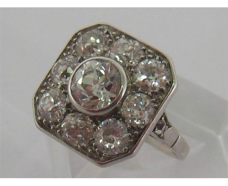 An Art Deco diamond and platinum plaque ring, the central old cut approx. 0.8 carat, above a surround of eight old cuts each 