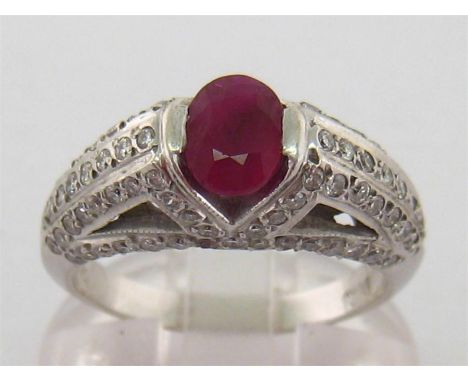 An 18 carat white gold, ruby and diamond ring, the oval cut stone 6.7mm long, above shoulders and mount pave set overall with