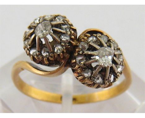 An early 20th century diamond cross over ring, the double cluster composed of two old brilliants in a surround of rose cuts, 