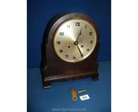 A wooden cased mantle Clock with key and pendulum, 13'' tall x 11'' wide.