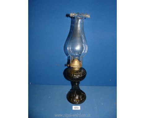 An oil Lamp with smoky brown glass base incorporating the reservoir, with fluted rim chimney, 17'' tall overall.