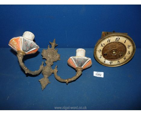 An old clock face and a brass wall light with ceramic candle holder.