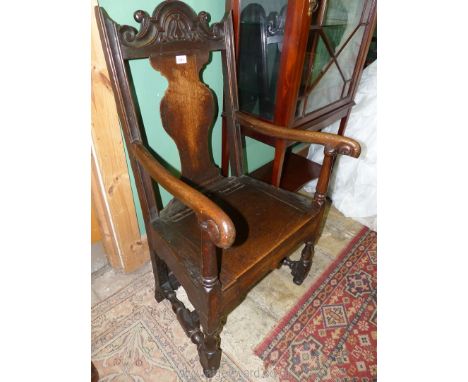 An early dark Oak framed Commode Armchair standing on turned legs and stretchers and with scroll terminating arms (one a/f), 