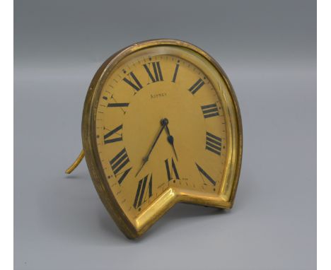 An Asprey Strut clock, the shaped brass case with gilded dial and Roman numerals, 10cms tall 