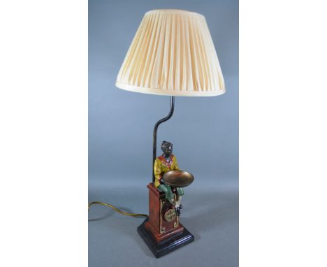 A painted metal table lamp in the form of a figure with a bowl upon a plinth with marble base, 30cms tall 