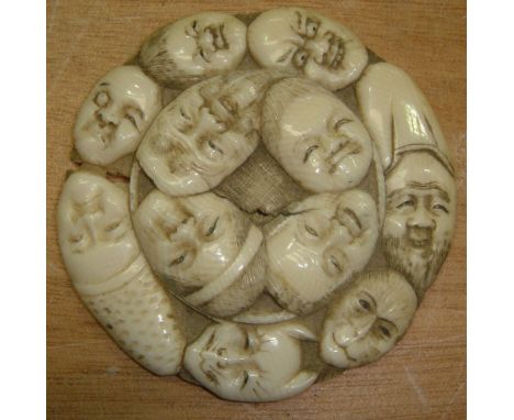 19th century Japanese carved ivory netsuke of circular form depicting 11 faces with crane on reverse 6 cms in diameter (some 