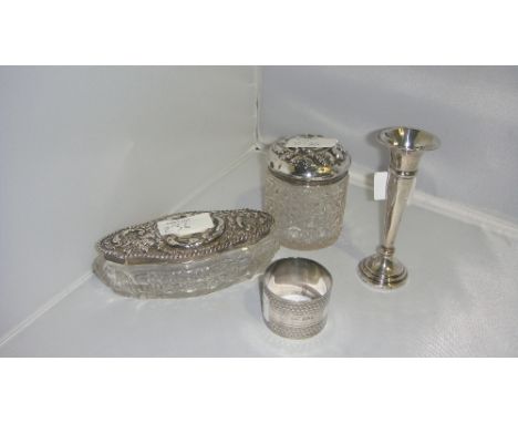 Silver serviette ring, filled silver spill vase, and two cut glass dressing table jars with embossed silver lids decorated wi