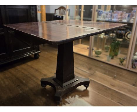 A Regency mahogany fold over pedestal card table. Having a top that twists and opens to reveal the playing surface, over a pl