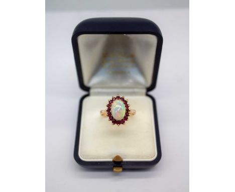 9ct Gold Opal and Ruby Ring  The ring has an Opal in the centre that measures approx. 11mm x 7.68mm.  The opal is showing a s