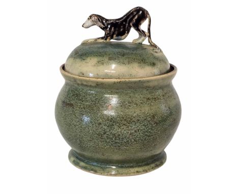 A Dagmar Dierick ceramic lidded pot. In tones of green with a glazed bronzed interior. The lid topped with a crouching Borzoi
